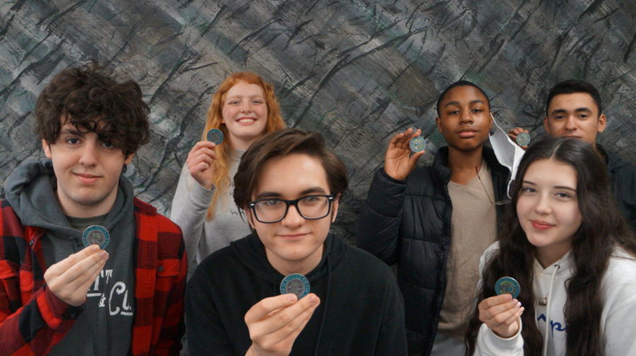 In-person Voyager students show their City of Rockford Challenge Coins. Front row: Gavin Overbey, Ewan Bickford, Alexa Rodriguez-Rodriguez. Back row: Maren Blakeney, Shanyis Jernigan, Jackson Motos.