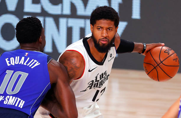 LAKE BUENA VISTA, FLORIDA - AUGUST 21: Paul George #13 of the LA Clippers looks to pass against Dorian Finney-Smith #10 of the Dallas Mavericks during the fourth quarter in Game Three of the Western Conference First Round during the 2020 NBA Playoffs at AdventHealth Arena at ESPN Wide World Of Sports Complex on August 21, 2020 in Lake Buena Vista, Florida. NOTE TO USER: User expressly acknowledges and agrees that, by downloading and or using this photograph, User is consenting to the terms and conditions of the Getty Images License Agreement. (Photo by Mike Ehrmann/Getty Images)